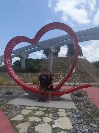 Pareja abrazada frente a un monumento en forma de corazón en Santo Domingo